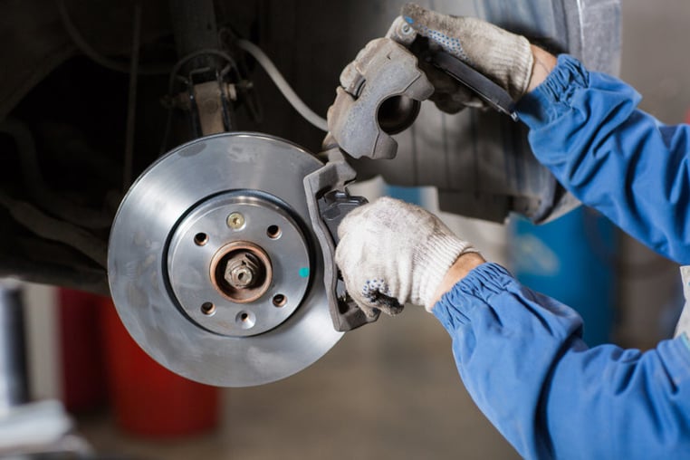 Inspecting brake pads to fix squeaky brakes on a car