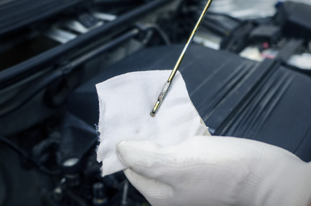 Close-up of a hand demonstrating how to read an oil dipstick accurately